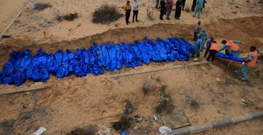 TOPSHOT - Palestinians bury bodies in a mass grave in Khan Yunis cemetery, in the southern Gaza Strip on November 22, 2023, amid ongoing battles between Israel and the Palestinian Hamas movement. The remains, which bore only numbers, had come from the Indonesian and Al-Shifa hospitals in the northern Gaza Strip, according to members of the committee at the burial site. (Photo by Mahmud HAMS / AFP)
