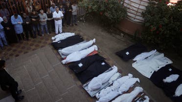 Palestinians pray near the wrapped bodies of relatives killed in the Israeli bombardment of the Gaza Strip, outside a morgue in Khan Younis, January 7, 2024. (AP)
