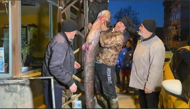 الرجلان التركيان يعرضان السمكة للناس في مكان إقامتهما