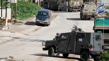 An Israeli soldier stands guard while a military vehicle blocks the road during a raid in Faraa refugee camp, near Tubas in the Israeli-occupied West Bank, January 13, 2024. (Reuters)