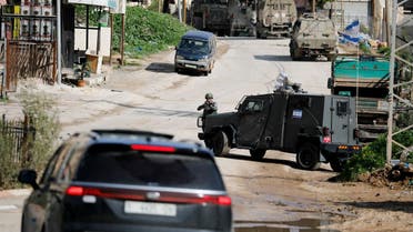 An Israeli soldier points his weapon while a military vehicle blocks the road during a raid in Faraa refugee camp, near Tubas in the Israeli-occupied West Bank, January 13, 2024. (Reuters)