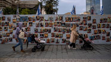 People walk next to a wall with photographs of hostages, mostly Israeli civilians who were abducted during the Oct. 7 Hamas attack on Israel, in Tel Aviv, Israel, Wednesday, Jan. 31, 2024. (AP Photo/Oded Balilty)