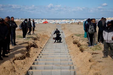 People prepare to bury Palestinians, including those who were killed in Israeli strikes and fire, after their bodies were released by Israel, according to Palestinian health ministry officials, amid the ongoing conflict between Israel and Hamas, at a mass grave in Rafah, in the southern Gaza Strip, on January 30, 2024. (Reuters)