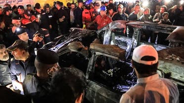 People, rescuers and security forces gather around a vehicle hit by a drone strike, reportedly killing three people, including two leaders of a pro-Iran group, in Baghdad on February 7, 2024. (AFP)