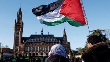 FILE PHOTO: Protesters hold a Palestinian flag as they gather outside the International Court of Justice (ICJ) as judges rule on emergency measures against Israel following accusations by South Africa that the Israeli military operation in Gaza is a state-led genocide, in The Hague, Netherlands, January 26, 2024. REUTERS/Piroschka van de Wouw/File Photo