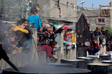 أطفال فلسطينيون ينتظرون الحصول على الطعام الذي أعده مطبخ خيري في رفح (رويترز)