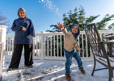 Omar Abu Kuwaik throws snow shortly after arriving from Gaza at the residence of the Global Medical Relief Fund as Khaolah Obahi of Rahma Worldwide looks on, Wednesday, Jan. 17, 2024, in the Staten Island borough of New York. The snow was the first that the 4-year-old had ever experienced. (AP)