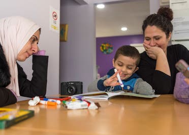 Four-year-old Omar Abu Kuwaik, center, works on activities in a math workbook with clinical social worker Sandy Lulu, right, as his aunt Maha Abu Kuwaik looks on, at the Global Medical Relief Fund residence, Sunday, Feb. 11, 2024, in the Staten Island borough of New York. (AP)