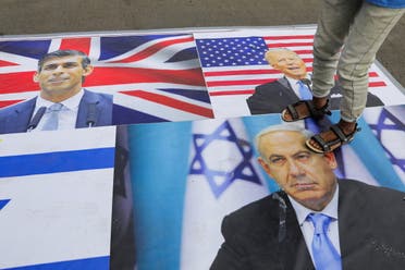 A person stands on the pictures of Israeli Prime Minister Benjamin Netanyahu, British Prime Minister Rishi Sunak and U.S. President Joe Biden as Houthi recruits parade in a show of force amid a standoff in the Red Sea and U.S.-led airstrikes on Houthi targets, in Sanaa, Yemen, February 8, 2024.