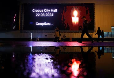 People walk past an electronic screen displaying a message in memory of the victims of a shooting attack at the Crocus City Hall concert venue, in the Moscow Region, Russia, March 23, 2024. (Reuters)