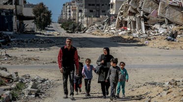 A Palestinian family walk past buildings destroyed in previous Israeli strikes in Gaza City, on March 25, 2024, amid the ongoing conflict between Israel and the Palestinian Hamas movement. (AFP)