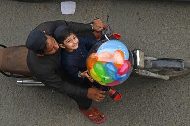 A boy carries a balloon on a motorbike after offering Eid al-Fitr prayers, marking the end of the holy fasting month of Ramadan, in Karachi on April 10, 2024. (AFP)