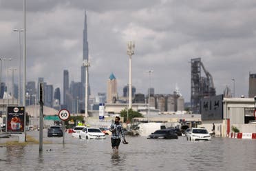 A person walks in flood water caused by heavy rains, with the Burj Khalifa tower visible in the background, in Dubai, United Arab Emirates, April 17, 2024. (Reuters)