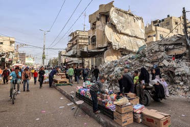 A boy helps a vendor arrange his merchandise as he sets up before the rubble of a collapsed building in Rafah in the southern Gaza Strip on April 23, 2024 amid the ongoing conflict in the Palestinian territory between Israel and Hamas. (AFP)