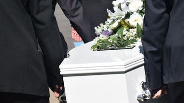 Men carrying casket during funeral procession. (Stock photo)