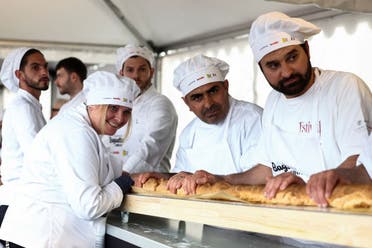 French bakers stand near a large rotating oven in an attempt to beat the world record for the longest baguette during the Suresnes Baguette Show in Suresnes near Paris, France, May 5, 2024. (Reuters)