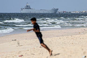 A child plays on the coast of Gaza as a ship transporting international humanitarian aid is moored at the US-built pier, May 21, 2024. (AFP)