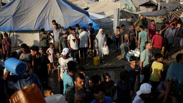 Palestinos desplazados por el bombardeo israelí de la Franja de Gaza hacen cola para recibir agua en un campamento de tiendas de campaña improvisado en la ciudad sureña de Khan Younis, el 1 de julio de 2024. (AP)