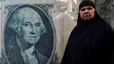 A woman stands next to a currency exchange point, displaying an image of the U.S. dollar, in Cairo, Egypt, March 6, 2024. REUTERS/Mohamed Abd El Ghany