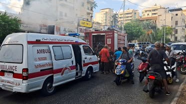 People gather as smoke rises from a mobile shop in Sidon, Lebanon on September 18, 2024. (Reuters)