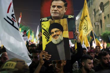 A person holds a picture of late leader of Lebanon’s Hezbollah, Hassan Nasrallah, next to a picture of Iranian IRGC commander Abbas Nilforoushan, who was killed in the Israeli strikes on Beirut, during Nilforoushan’s funeral in Kerbala, Iraq, October 14, 2024. (Reuters)