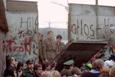 This Nov. 11, 1989 photo shows East German border guards looking through a hole in the Berlin Wall after demonstrators pulled down one segment of the wall at Brandenburg Gate. (File photo: AP)