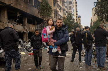 A man carries his daughter to her school as he walks past a damaged building in the aftermath of an Israeli strike, amid the ongoing hostilities between Hezbollah and Israeli forces, in Beirut's Mar Elias street, Lebanon November 18, 2024. (Reuters)