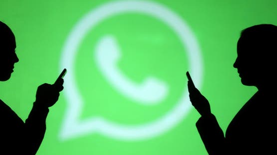Silhouettes of mobile users are seen next to a screen projection of Whatsapp logo in this picture illustration taken March 28, 2018. REUTERS/Dado Ruvic/Illustration